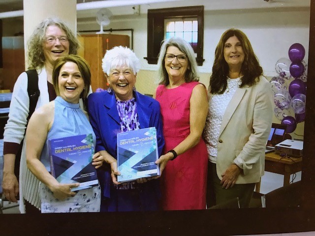 Lynda Mckeown Group Photo Lynda McKeown with copy Dental Hygiene textbook and unidentified individuals