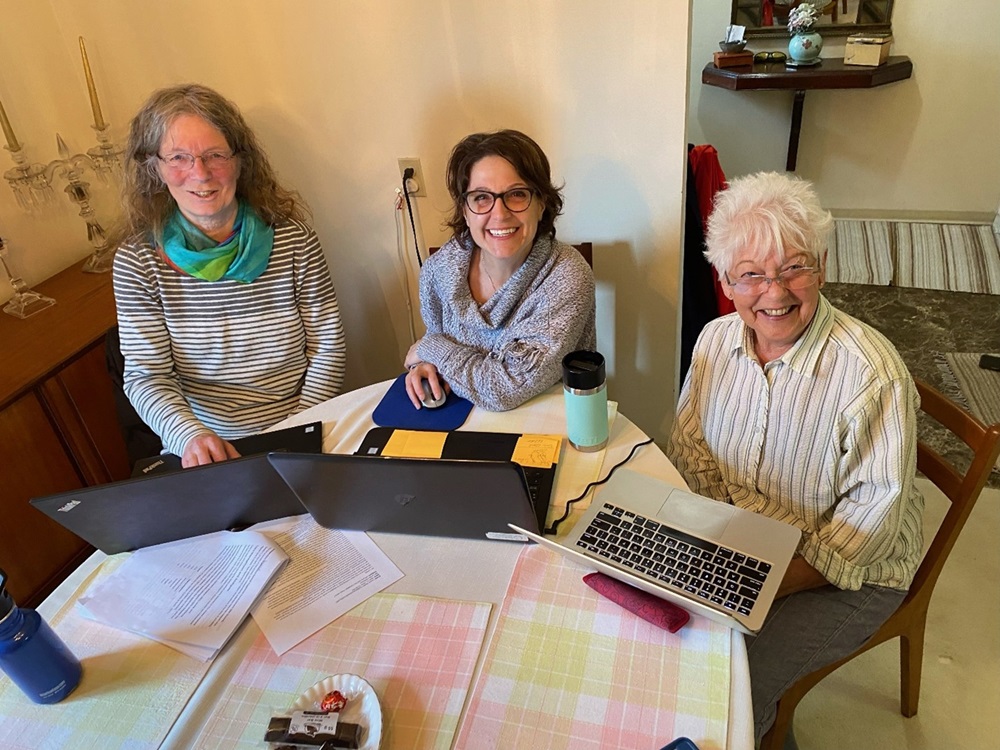 Lynda McKeown at Work Lynda McKeown sitting at table with laptops and unidentified individuals