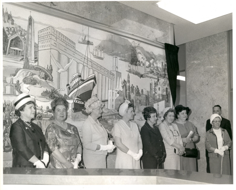 Mural at City Hall, 1966 A group of people standing in front of a mural indoors wearing fancy attire