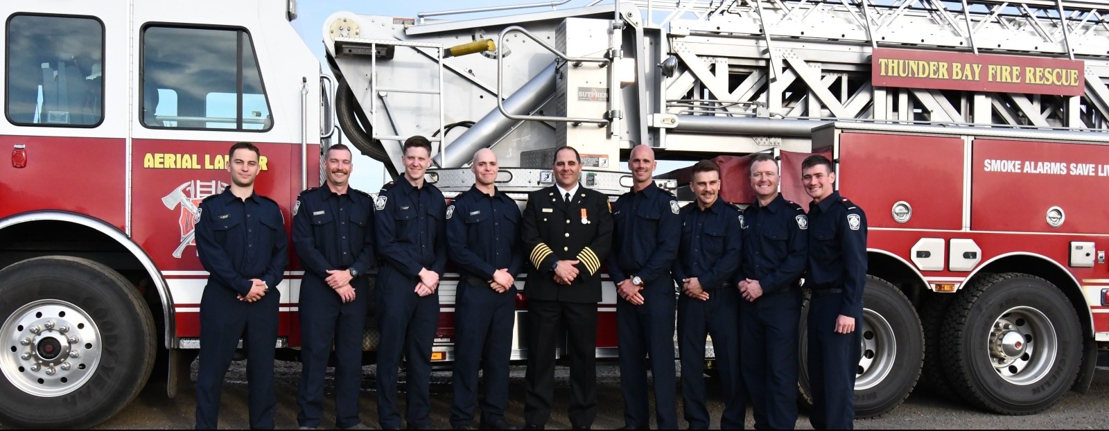 Firefighters pose in front of a truck